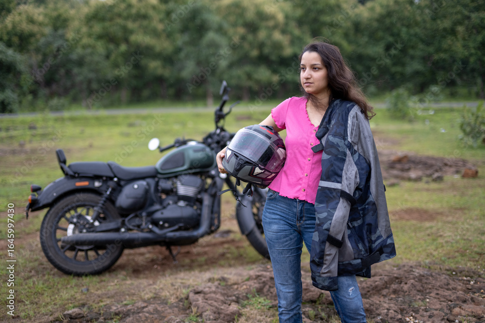 Fototapeta premium Strong independent Indian woman biker: beautiful girl, stylish rider, motorcycle adventure, elegant jacket, confident posture, powerful machine, free spirit, road journey, fearless attitude.