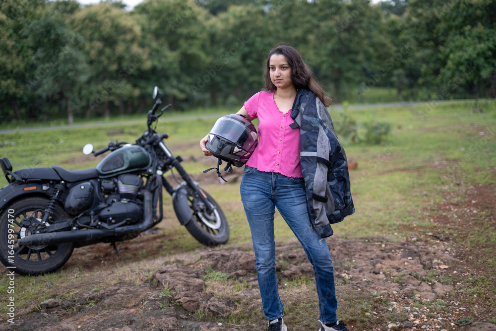 Fototapeta premium Strong independent Indian woman biker: beautiful girl, stylish rider, motorcycle adventure, elegant jacket, confident posture, powerful machine, free spirit, road journey, fearless attitude.