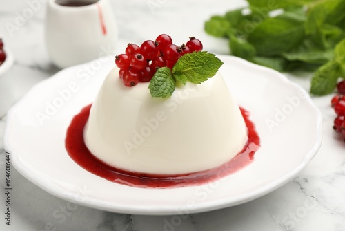Fotografie Delicious panna cotta with red currants, sauce and mint on white marble table, c