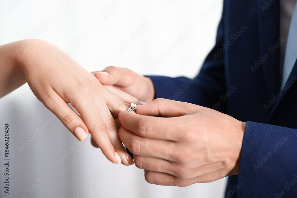 Making proposal. Man putting engagement ring on his girlfriend's finger indoors, closeup Making proposal. Man putting engagement ring on his girlfriend's finger indoors, closeup