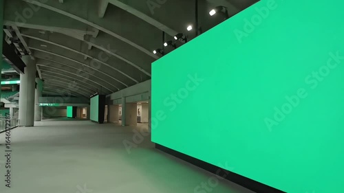 Futuristic exhibition hall featuring a massive green chroma key LED screen for mockup and digital content