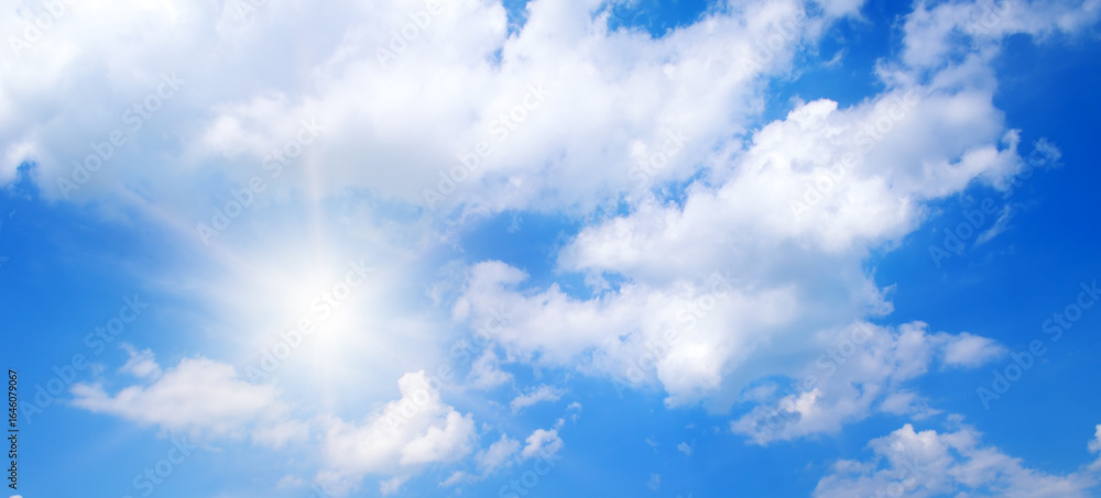 Obraz premium Bright sun and white clouds in clear blue sky on summer day.