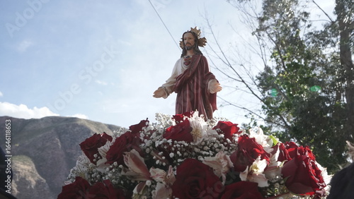 Small image of the Sacred Heart of Jesus carried in a basket, with the sky and sun rays in the background