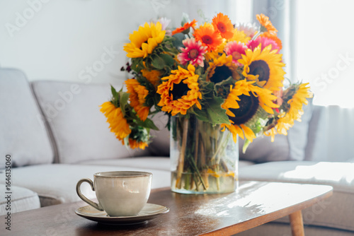 Wallpaper Mural Focus on cup of hot drink and vase with huge sunflowers bouquet on wooden coffee table in modern cozy light living room with gray couch sofa. Cozy Design home decor. Summer mood, Relaxing rituals. Torontodigital.ca