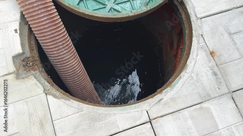 Technicians are engaged in servicing a septic system, inspecting and cleaning the drainage pit. Septic tank service. Sewage Tank truck.