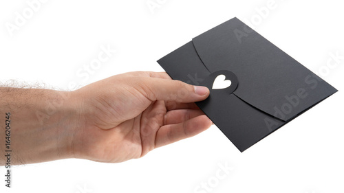 Person handing over a black envelope with a heart cutout to express affection or hidden message during a heartfelt moment