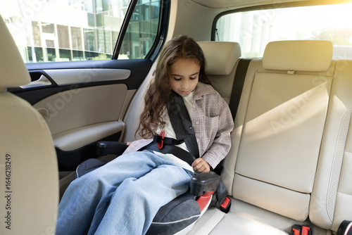 Dark-haired cute girl sitting in a car with her safety belt fixed