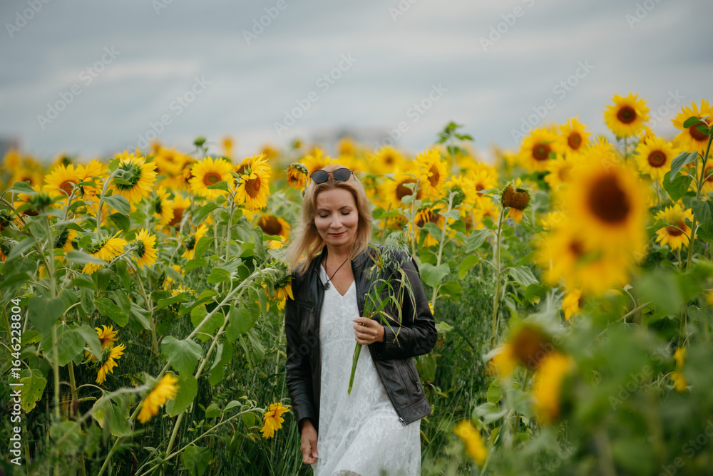 Fototapeta premium A woman walking through a field of sunflowers