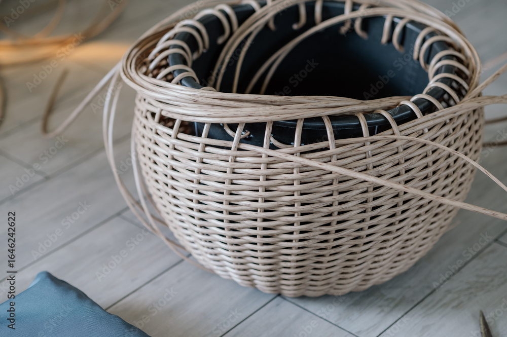 Obraz premium Rattan basket in the process of weaving. A woman's hobby. Natural textures and patterns that create a rustic and organic aesthetic. Perfect for home decor, storage, and organization