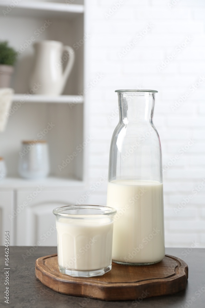 Dairy products. Fresh milk in glass and bottle on gray textured table indoors Dairy products. Fresh milk in glass and bottle on gray textured table indoors