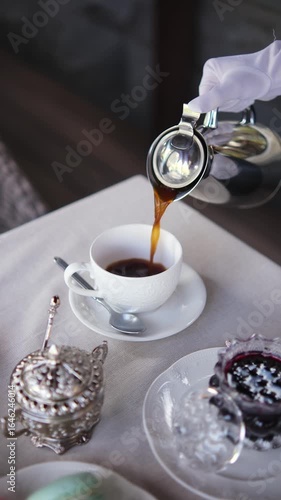 Pouring black coffee from a steel coffee pot