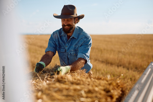 Canvas Print Happy farmer loading hale bales in back of his truck.