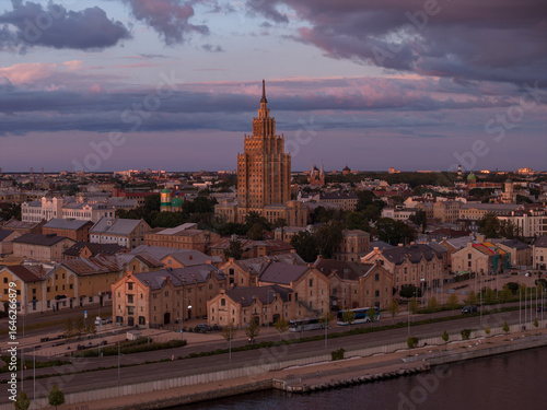 Wallpaper Mural The Latvian Academy of Sciences stands at the center, surrounded by historic buildings. A waterfront area and soft pink and purple skies complete the scene. Torontodigital.ca