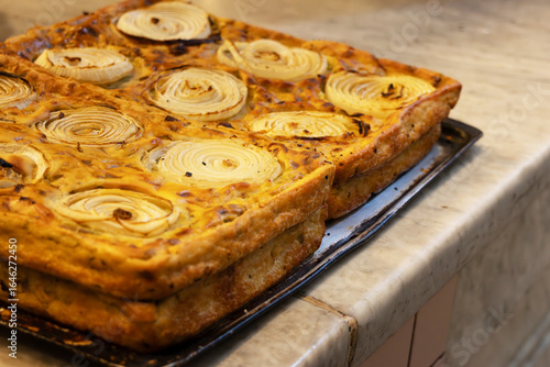 A baking sheet with golden onion pie on a countertop