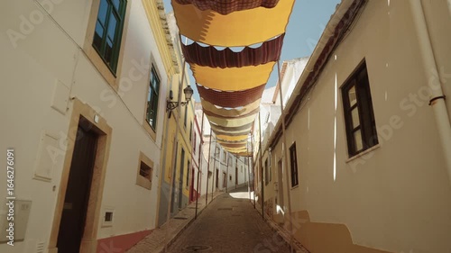 Colorful fabric shades over narrow cobblestone street in a Portuguese town