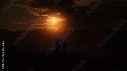 A couple walks at sunset in the fog