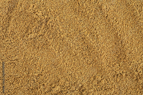 Ground coriander seeds seasoning as background, top view. Coriander powder, spices.
