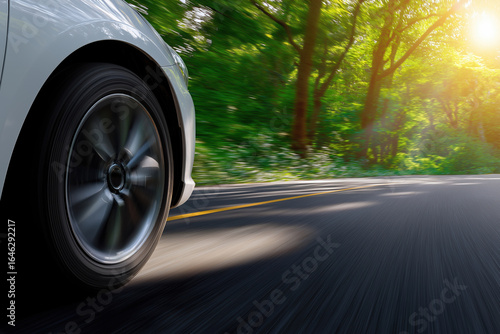 Car driving on a winding road surrounded by lush greenery during sunset
