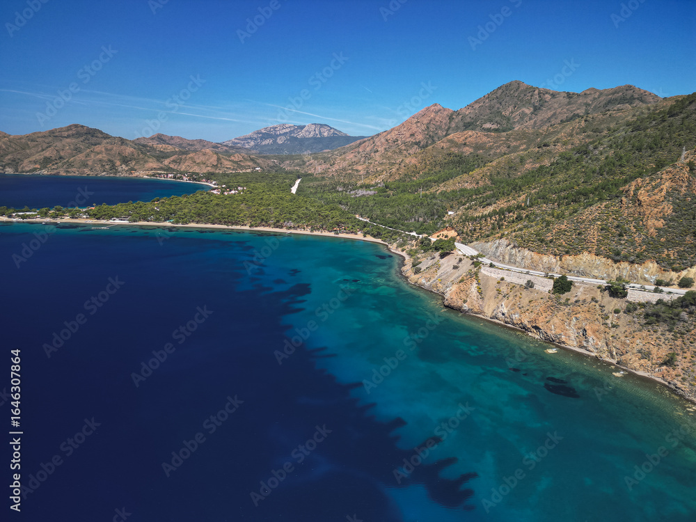 Obraz premium Aerial view reveals secluded natural cove featuring brilliant emerald waters surrounded by lush Mediterranean vegetation creating hidden coastal gem