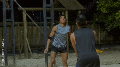 Male Volleyball Players Competing on Outdoor Sand Court at Night