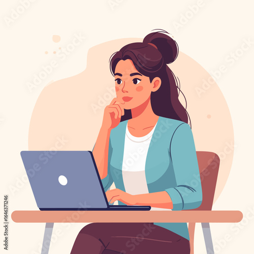 Thoughtful young woman with a messy bun hairstyle working on a laptop, wearing a blue cardigan.