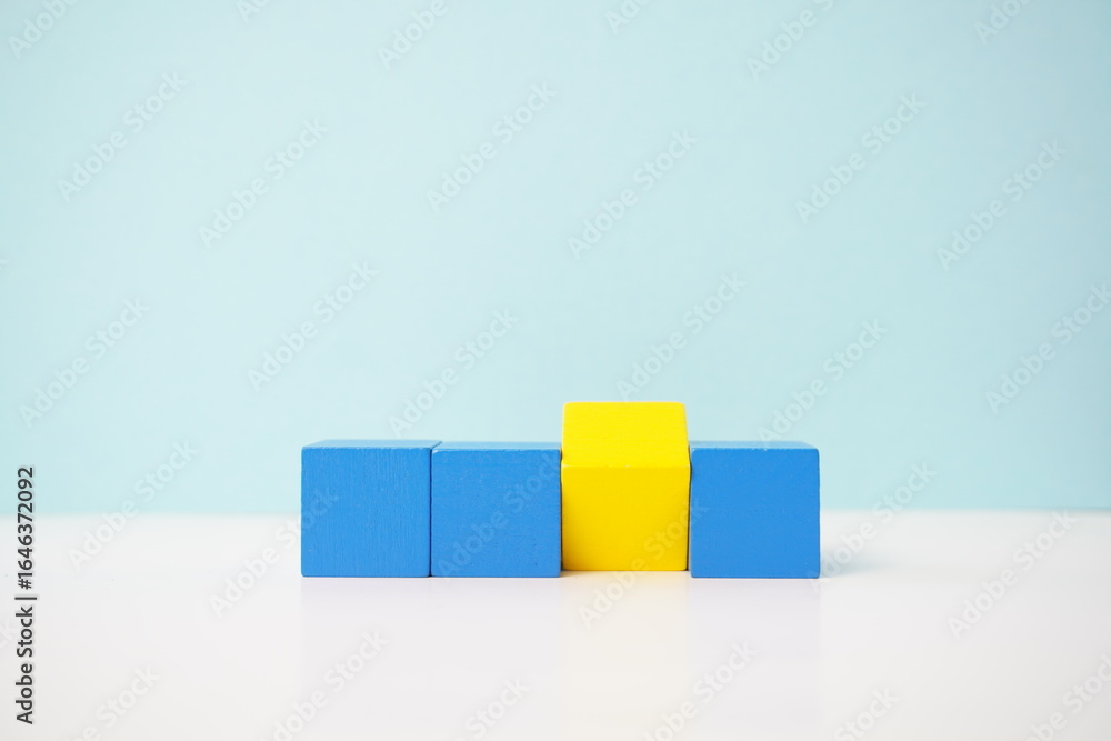 Obraz premium Yellow cube among blue cubes reflecting individuality or difference for educational or conceptual applications. strategy, business, economy and educational concepts