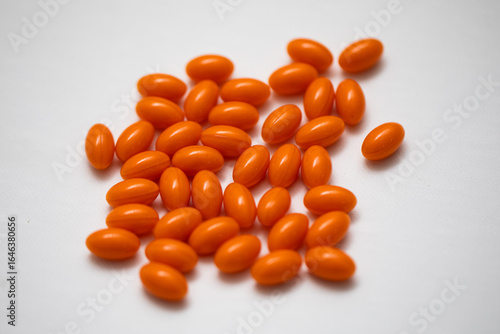 Bright orange coenzyme q10 dietary supplement pill medicine on white background in the center 