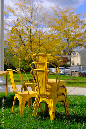 Yellow chairs stacked on a green lawn