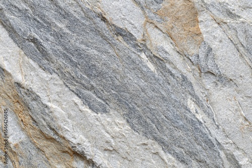 Close-up view of a stone surface with varied shades of gray, beige, and white.  Textured, rough surface with prominent diagonal lines