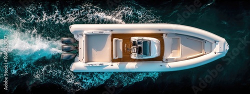 High-angle view of a white rigid inflatable boat (RIB) on the water.  Water splashes around the boat's stern. 