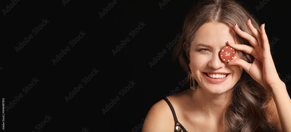 Fototapeta premium Beautiful young woman with poker chip on dark background with space for text