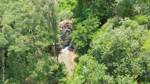 Aerial top-down view of a hidden creek in a dense jungle valley, Looking down on a rocky waterfall from the canopy, Unspoiled nature of a tropical rainforest stream