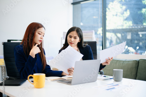 Two business women of young and middle age talking working in Teamwork Finance, Marketing at the office.