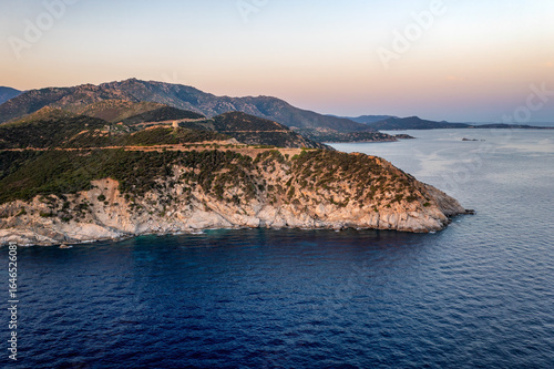 Drone aerial view of Capo Boi coastline at sunset with turquoise