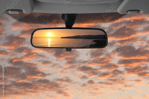 Sunset landscape reflected in the car rear view mirror
