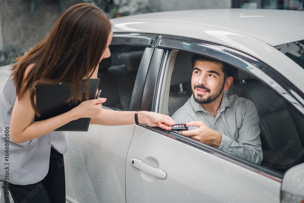 Fototapeta premium Car sales agent handing key to customer inside new car, showing final delivery moment, trusted service, professional consultation, and customer satisfaction in automotive purchase process.