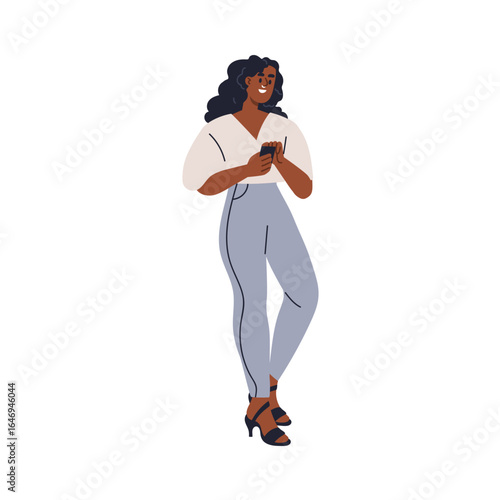 Happy black woman holding mobile phone in hands. Young female standing outdoo...