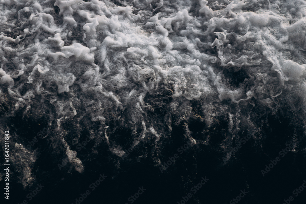 Obraz premium A close-up, abstract view of churning sea foam and waves, showing the dynamic texture and movement of the ocean water.