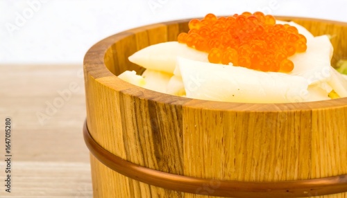 Wooden bowl filled with white fish slices and orange fish roe