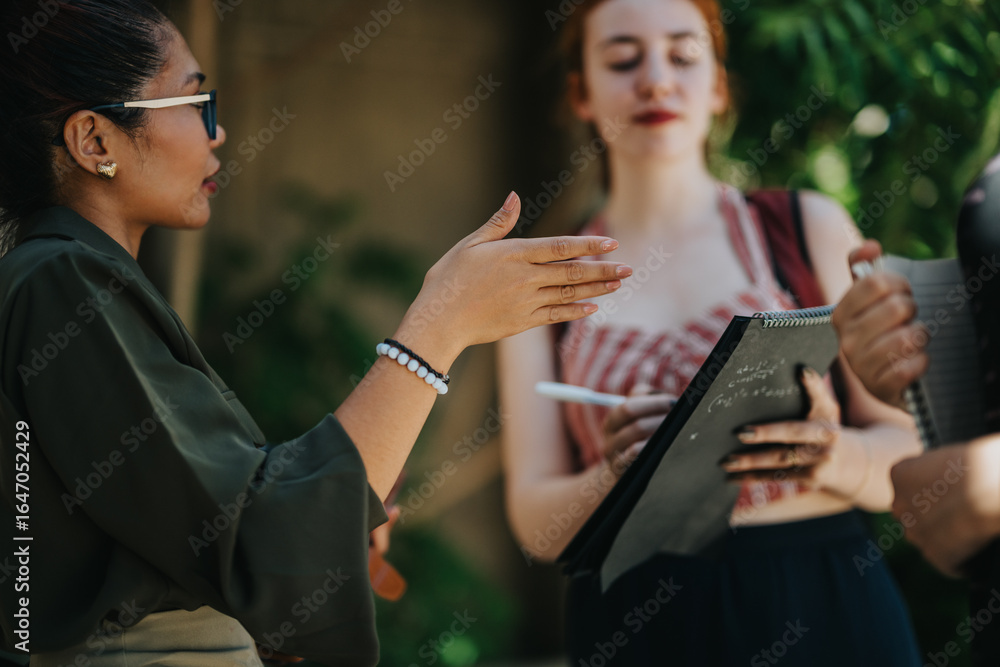 Fototapeta premium Engaging educational activity taking place in a school courtyard with teacher and students collaborating. The professor facilitates a discussion while students take important notes.