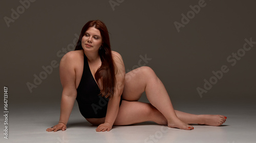 A plus-size woman confidently poses in a black swimsuit, promoting body positivity and empowerment. Concept of embracing self-image and diversity in fashion.