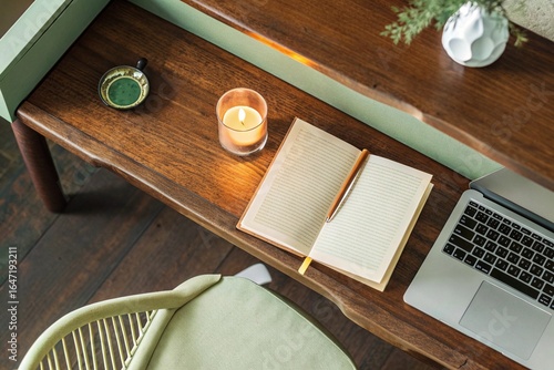 Cozy Work Corner: Overhead view of a warm-toned desk with a candle, book, coffee cup, and laptop