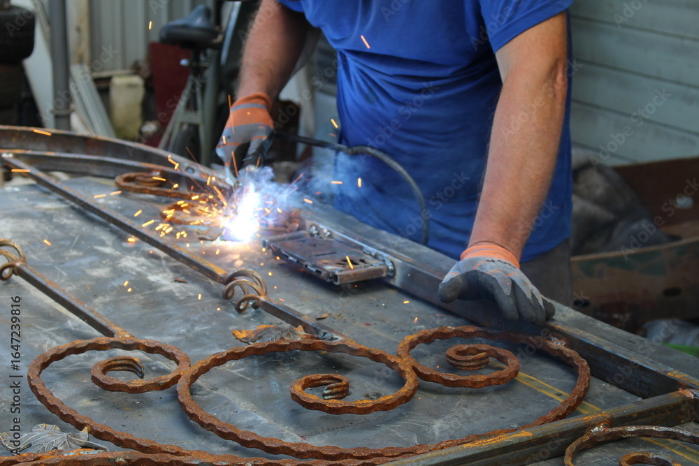 Fototapeta premium A man works with a welding machine and makes beautiful gates from forged metal.