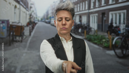 Wallpaper Mural Caucasian woman with short hair and neutral expression pointing finger to street lined with brick buildings; determination direction. Torontodigital.ca