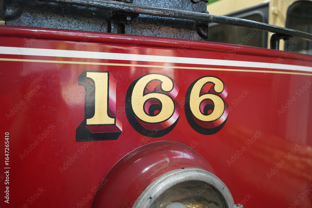 Obraz premium Crich Tramway Museum, England - August 13 2025: Vintage red tram number 166 detailed close-up at the museum.