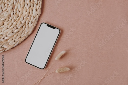 Black smartphone with blank screen on decorative dry grass arrangement