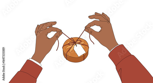 Hands carefully tying a ribbon around a round gift wrapped with twine and a blank gift tag attached for a special occasion