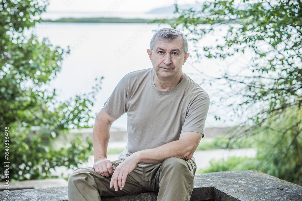 Fototapeta premium Pensive European senior man, emotional portrait of reflection and life challenges. Emotive portrait of a 55–65 year old man outdoors