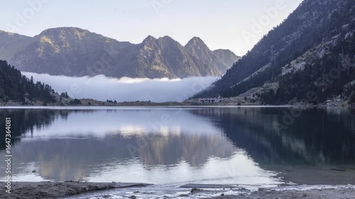 timelapse mist and clouds coming from the valley at sunrise over lac de gaube in the Pyrenees mountains France on a summer day