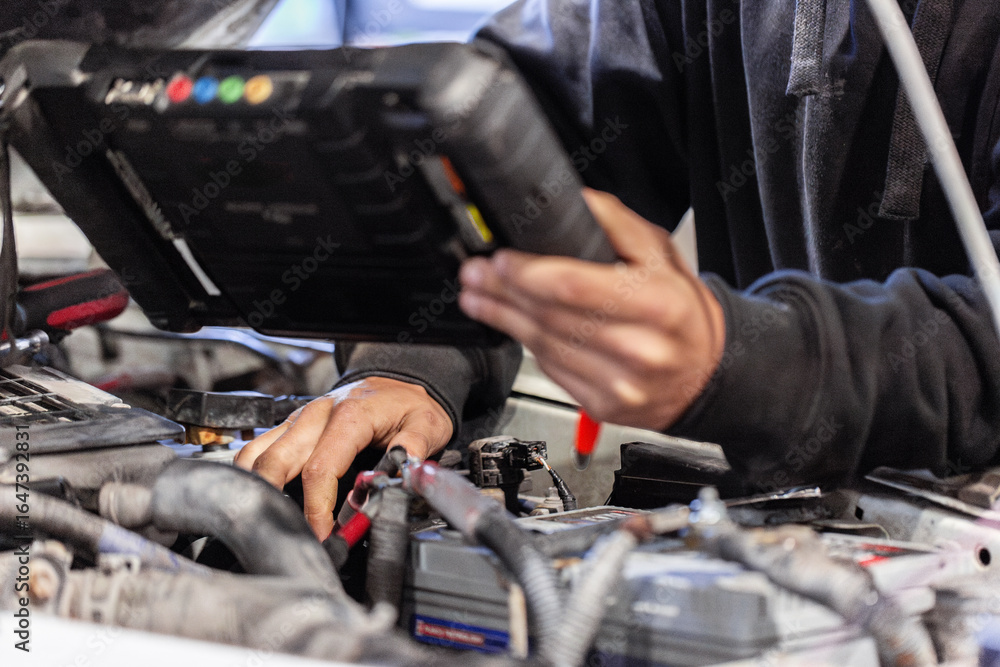 Aussie workman using digital diagnostics tool working on car vehicle engine in mechanics workshop Aussie workman using digital diagnostics tool working on car vehicle engine in mechanics workshop